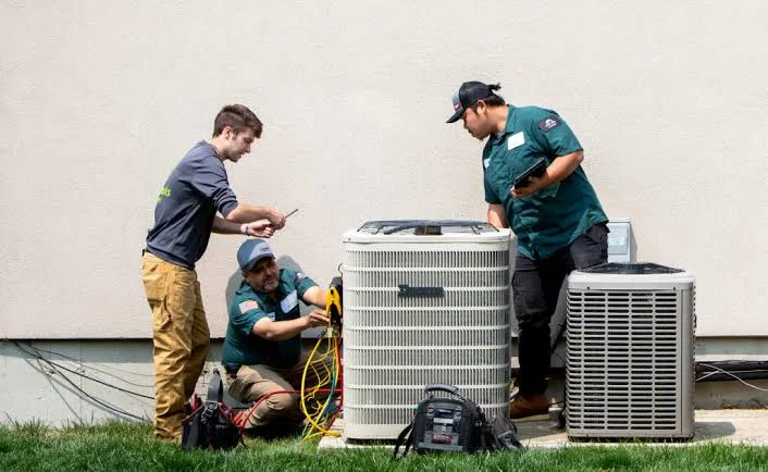 HVAC service team working together on residential outdoor cooling equipment