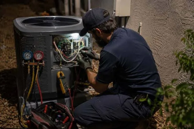 HVAC technician performing detailed diagnostics on an outdoor AC condenser