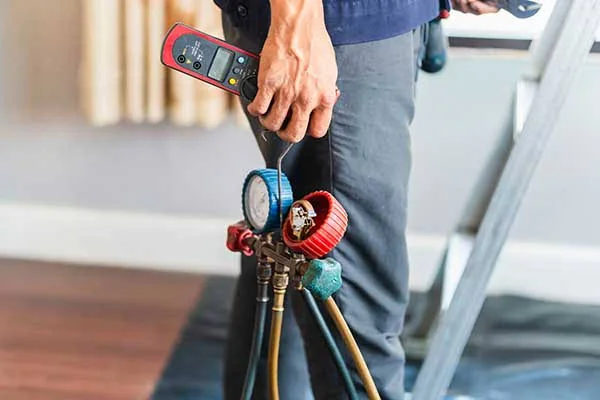 HVAC technician carrying manifold gauges for preventative system maintenance